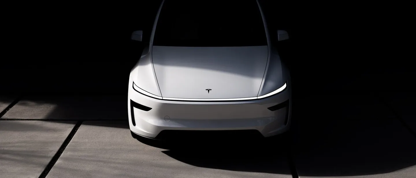 Karanlık bir zeminde önden görünen beyaz Tesla otomobil.