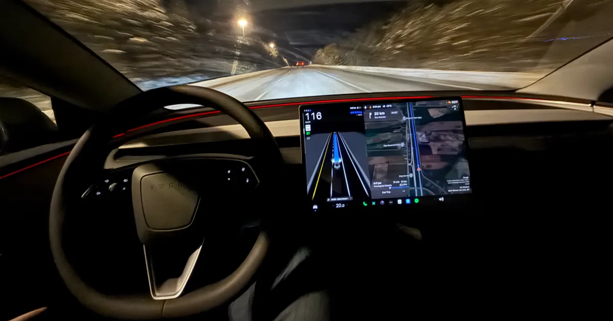 Tesla’nın ön konsolu ve orta ekranında sürüş ve yol bilgileri görünüyor; ön camın dışında tünel benzeri bir yol var.