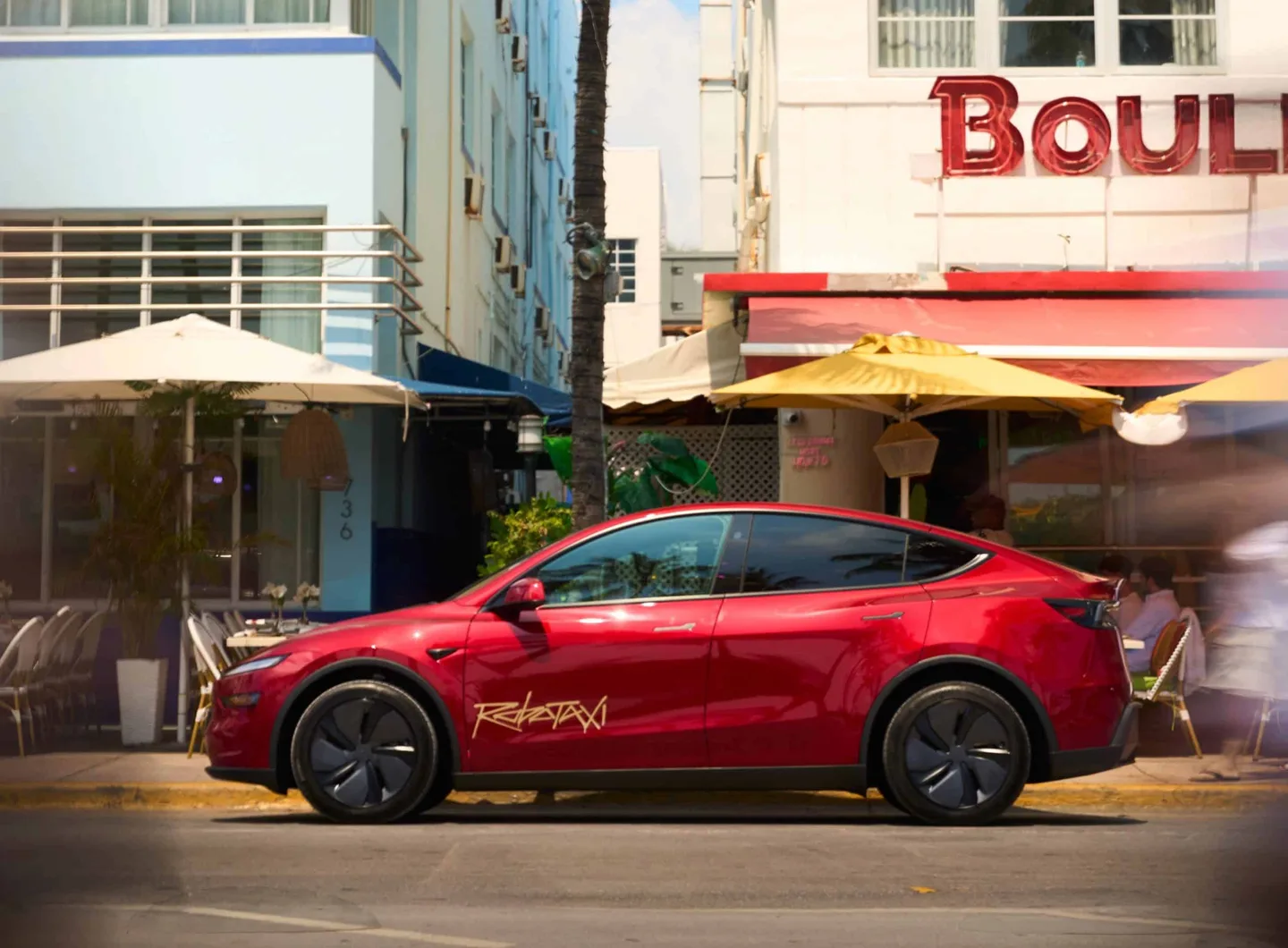 Şehir sokağında park hâlindeki kırmızı Tesla.