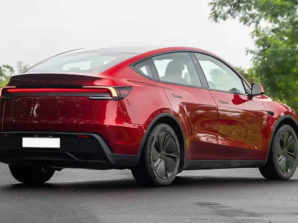 Kırmızı Tesla Model Y’nin arkadan ve yandan görünümü.
