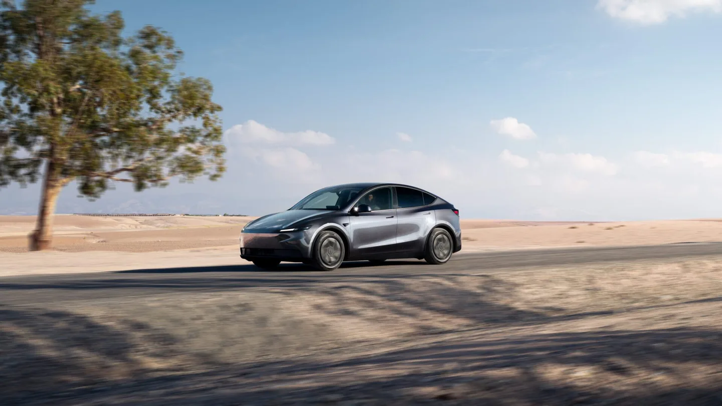 Açık arazide yolda ilerleyen gri Tesla Model Y.