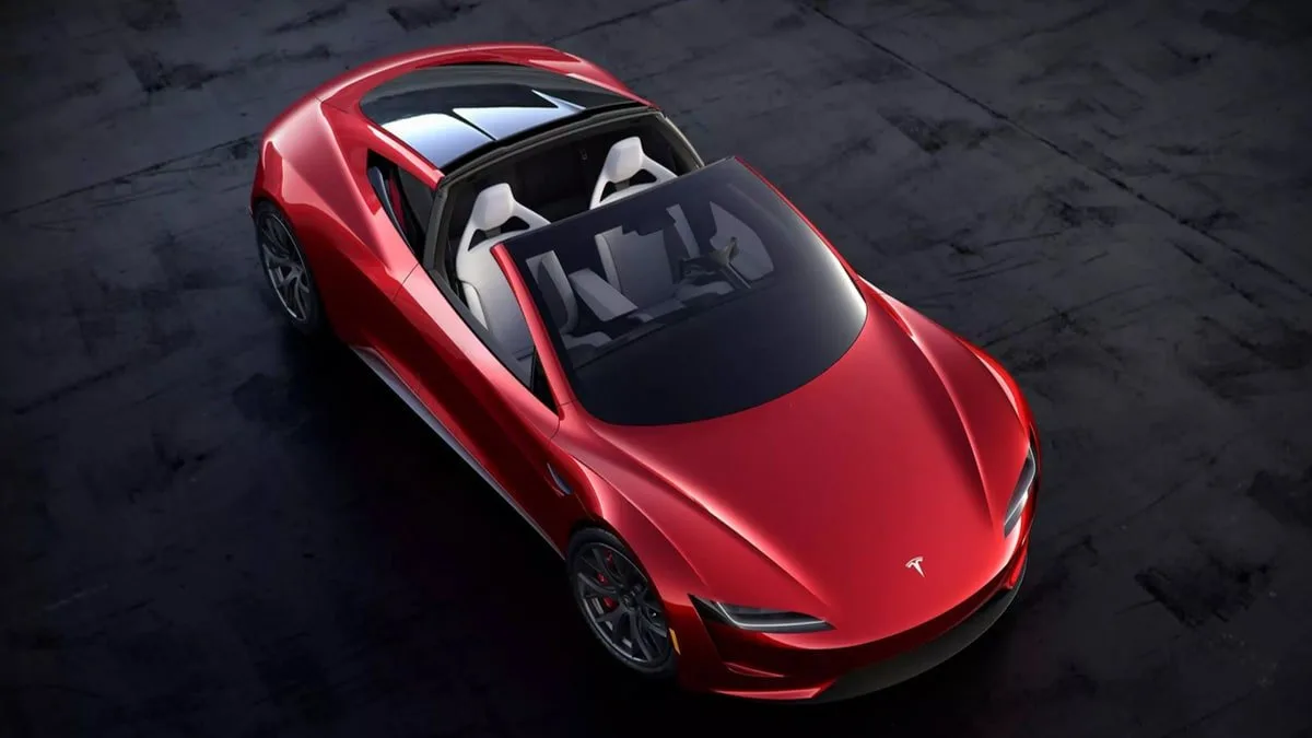 Koyu zeminde, yukarıdan açıyla görünen kırmızı Tesla Roadster.
