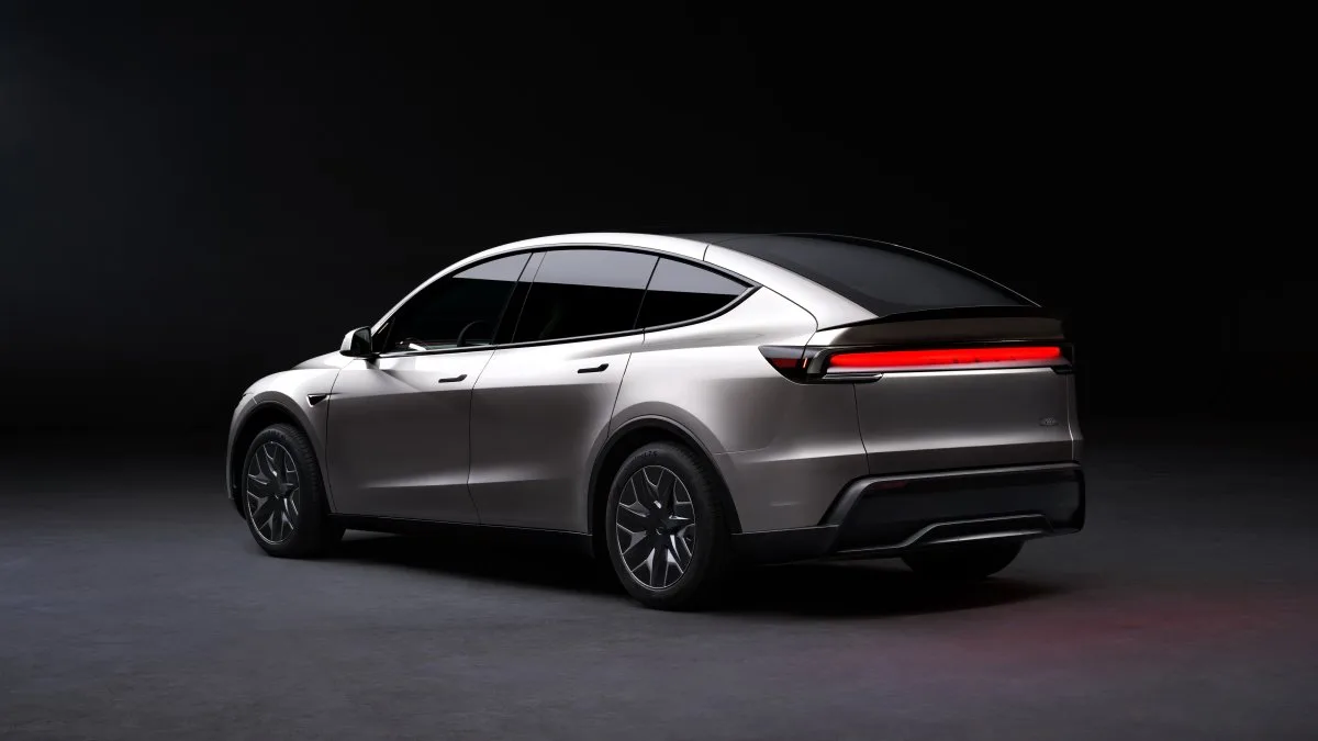Koyu fonda, arkadan ve yandan görünen gümüş renkli Tesla Model Y L.