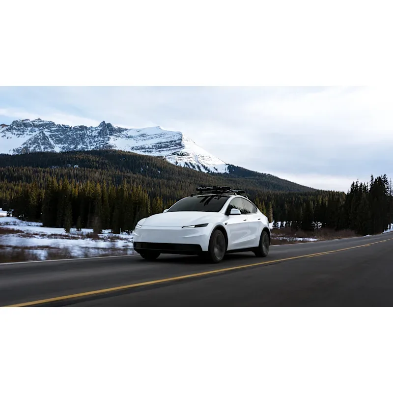Karlı dağların önündeki yolda ilerleyen beyaz Tesla Model Y. · arşiv görseli